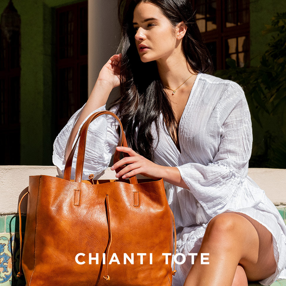 Woman holding a brown leather tote bag with 'Chianti Tote' text, wearing a white dress.