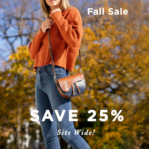 Person wearing an orange sweater and blue jeans with a brown leather bag, standing in front of trees with autumn foliage. 'Fall Sale' and 'Save 25% Site Wide!' text overlay.