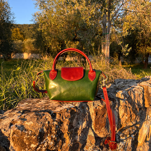 Floto Gattane Green handbag with brown handles and strap on a stone surface with a natural background