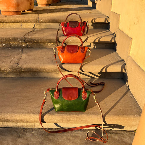 Floto Gattane Three handbags in red, brown, and green on stone steps.