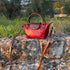 Floto Gattane Red handbag with brown strap on a stone wall in a natural setting