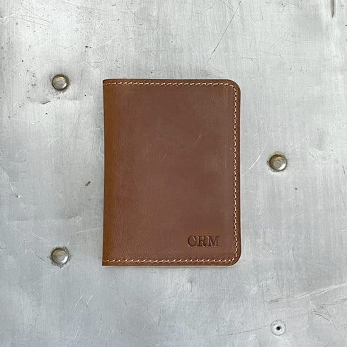 Brown leather wallet with 'CRM' engraving on a metallic surface