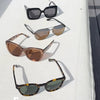 Four pairs of sunglasses on a white surface with a gray background