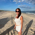Woman standing on a sandy beach with ocean and blue sky in the background